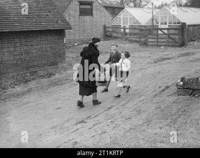 Les Carter en temps de guerre- la vie quotidienne d'une famille britannique sur le front intérieur, en Angleterre, C 1940 Michael et Angela Carter courir pour saluer leur mère à son arrivée à l'accueil des sinistrés à Hayward's Heath, dans le Sussex. Mme Carter a voyagé sur le train de Londres Victoria pour leur rendre visite. Banque D'Images