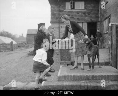 Les Carter en temps de guerre- la vie quotidienne d'une famille britannique sur le front intérieur, en Angleterre, C 1940 Mme Cluton, une "mère" pour de nombreuses personnes, se félicite Mme Carter à son domicile de Hayward's Heath. Les enfants de Mme Carter, Michael et Angela, ont été d'un séjour avec Mme Cluton à Hayward's Heath depuis leur évacuation à partir de Londres. Dans l'arrière-plan, plusieurs autres évacués, également cantonnés avec Mme Cluton, peut être vu. Banque D'Images