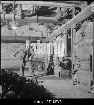 Les jardins de Kew- le travail de Kew Gardens en temps de guerre, Surrey, Angleterre, RU, 1943 R Halsey stokes une fournaise sous le grand Palm House à Kew Gardens. Selon la légende originale, ces fours (il y a deux stokeholds sous le Palm House) fournir de la chaleur à environ 13 kilomètres de canalisations d'eau chaude et brûler environ 800 tonnes de coke par an. Banque D'Images