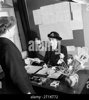 La jeune fille inconnue derrière la bataille de la mer- le travail de Women's Royal Naval Service, 1942 maintenant pleinement inscrits après deux semaines de formation, Wren Inconnu recueille son voyage européen et projets d'ordonnance de l'officier responsable du dépôt. Ces documents lui dire de base qui elle sera envoyée. Banque D'Images