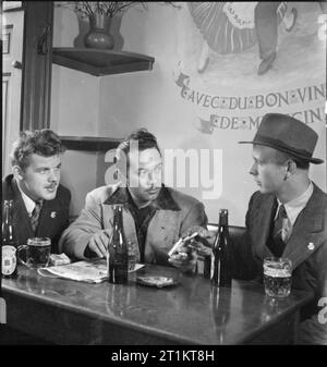 Les sept mers Club- La vie au Club de la marine marchande, Édimbourg, Écosse, 1943 Werner Petersen (à gauche) et Hans Christensen (droite) de Danemark inscrivez-vous Charles Andrade, un Américain à des marins marchands de Honolulu, pour prendre un verre et fumer dans le bar des Sept Mers Club à Édimbourg. Banque D'Images