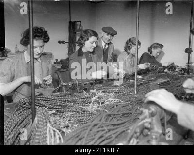 Ils combattent également qui seulement se tenir et attendre- industrie de guerre dans une ancienne maison de pays, 1942 travailleurs à temps partiel communication guerre lier les cordons dans le prix d'une maison de campagne qui a été converti à la production de guerre. La maison est la propriété de M. et Mme Clark et les travailleurs de la production de divers types d'équipements téléphoniques et de communication. Banque D'Images