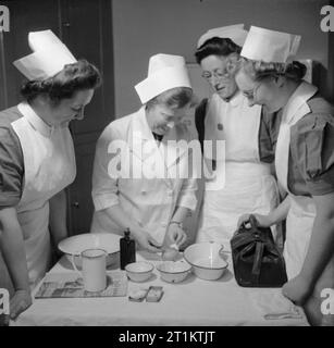 La formation des infirmiers et infirmières de district Queen- La formation des infirmières au Queen's Institute de soins infirmiers de district, Guildford, Surrey, Angleterre, RU, 1944, lors d'une classe à l'Institut de la Reine du District de soins infirmiers, de Soeur démontre l'utilisation d'une seringue hypodermique à un groupe de stagiaires. Elle est l'injection d'une pomme, comme la pénurie de guerre signifie qu'elle est incapable d'obtenir les oranges, qu'elle a l'habitude d'utiliser pour des démonstrations ! Banque D'Images