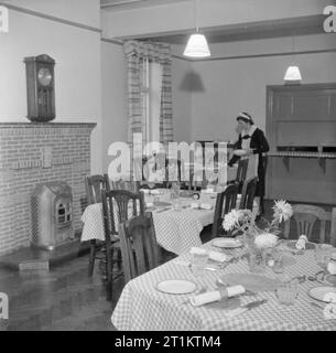 La formation des infirmiers et infirmières de district Queen- La formation des infirmières au Queen's Institute de soins infirmiers de district, Guildford, Surrey, Angleterre, RU, 1944 UNE FEMME jette les tables prêtes pour le déjeuner dans la salle à manger agréablement meublées de la maison des infirmières à l'Université Queen's, l'Institut de soins infirmiers de district de Guildford. Banque D'Images