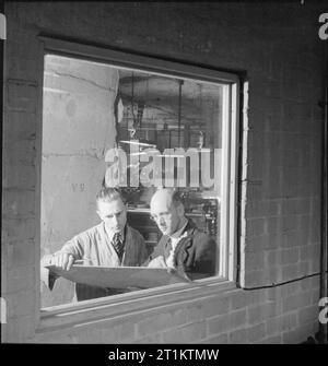 L'usine souterraine- la vie quotidienne dans une usine souterraine, probablement Printemps Carrière, Corsham, Wiltshire, Angleterre, 1942 Shop Surintendant Charles Tunstall (droite) donne des instructions à un travailleur au sujet de la journée de travail à l'usine souterraine. Banque D'Images