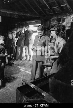 Les troupes américaines dans un village anglais- la vie quotidienne avec les Américains en Burton Bradstock, Dorset, Angleterre, RU, 1944 Le Master Sergeant Edward White (de 991 S.San Antonio Street, Pomona, Californie) examine un fer à cheval donné par blacksmith R Burton dans l'atelier du forgeron dans Burton Bradstock, Dorset. Le sergent White et ses collègues Le sergent R J Baier (de 125 Park Avenue, Canandaigna, New York) et le Caporal David Roberts (de RR4 Albia, Iowa), accompagné par plusieurs garçons locaux, ont 'venez à mendier pour un jeu de fers au camp'. Banque D'Images