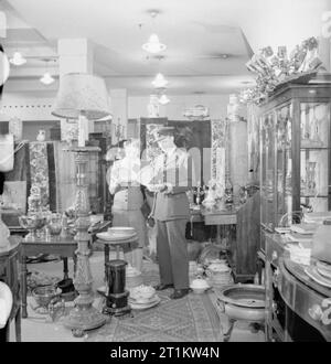 La vie de tous les jours- épouse de guerre en temps de guerre, Londres, mars 1943 Nouveaux fiancés Harold Lackland Bevan et Marcelle Lestrange examiner quelques morceaux de la Chine dans un magasin à Londres. Tous chine maintenant produits en utilité et du papier blanc. La Chine définit de couleur ont disparu à l'exception de certains d'autres stocks d'avant-guerre de Crown Derby et Coleport. Dîner de seconde main services sont donc en grande demande. Banque D'Images