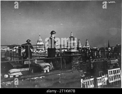 Vous répondre- la production d'un programme radio de la BBC pour les États-Unis d'Amérique, 1941 L'un des panélistes sur 'vous répondre' a été Edward Hulton, propriétaire d'une maison d'édition. Nous voyons ici Hulton (à droite) et un collègue en feu regarder droit sur le toit de son entreprise Hulton Press. Derrière eux on peut voir la ville de Londres, y compris l'ancien Bailey et la Cathédrale St Paul. Banque D'Images