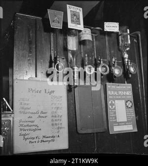 Pub de guerre- la vie quotidienne au Wynnstay Arms, Ruabon, Denbighshire, Wales, UK, 1944 vue de porte-bouteilles vides derrière le bar de l'Armes, Ruabon Wynnstay. Ce manque d'esprits, comme le whisky et le gin était une chose commune en temps de guerre. Aussi visible est une liste de prix pour les bières. La légende originale que le 'srampé, modification de la liste des prix montre l'augmentation du budget en verre prix". Une affiche invite les gens à faire don de leurs pièces d'un 'rural' pour la Croix-Rouge Agriculture Fund. Banque D'Images