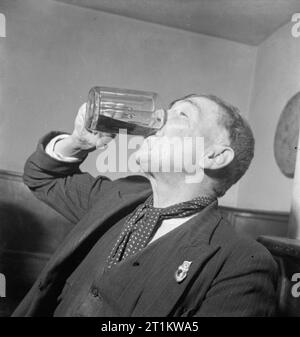 Pub de guerre- la vie quotidienne au Wynnstay Arms, Ruabon, Denbighshire, Wales, UK, 1944 ouvrier Local : Evans boissons sa pinte de bière au Wynnstay Arms in Ruabon. Selon la légende originale, M. Evans a dit : "Il peut être cher, il peut être mince, mais il n'y a pas de mauvaise bière". Banque D'Images