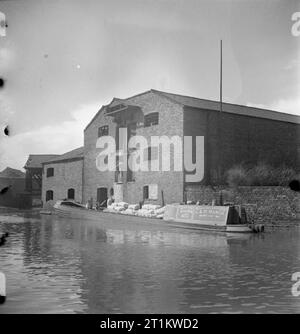 Les femmes dirigent un bateau- La Vie à bord de la Barge Canal 'Heather Bell', 1942 Une cargaison de farine sont déchargées de la 'HEATHER BELL' dans un entrepôt sur un canal, probablement le Canal de Birmingham à Tipton Junction. Banque D'Images