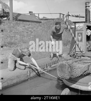 Les femmes dirigent un bateau- La Vie à bord de la Barge Canal 'Heather Bell', 1942 Miss Mars supprime les mauvaises herbes et autres déchets provenant du propulseur du 'HEATHER BELL' comme sa mère les regarde. Banque D'Images