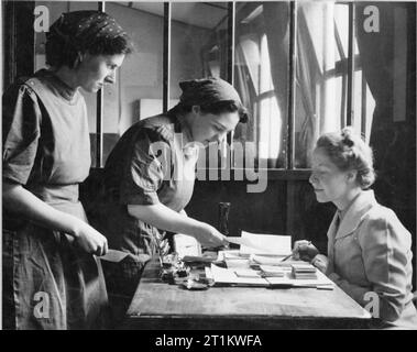 Usine de femmes le travail de guerre au centre de formation de Slough, Angleterre, Royaume-Uni, 1941 Deux travailleurs à la visite du centre de formation de Slough le superviseur de l'aide. Le superviseur est là pour aider avec les problèmes rencontrés par les stagiaires, que ce soit d'affaires ou de nature personnelle. Banque D'Images