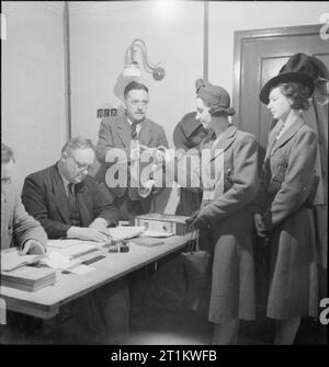 Usine de femmes le travail de guerre au centre de formation de Slough, Angleterre, Royaume-Uni, 1941 Rose Pridie et sa sœur Betty voir l'officier d'hébergement, qui prend les billets et transport pour eux à l'arrivée à Slough centre de formation. Banque D'Images