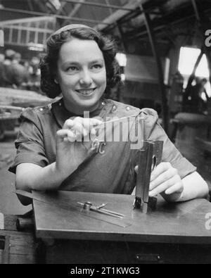 Usine de femmes le travail de guerre au centre de formation de Slough, Angleterre, Royaume-Uni, 1941 Betty Pridie mesure une charnière à Slough centre de formation. Les initiales "GTC" brodé sur son stand l'ensemble de 'centre de formation' du gouvernement. Banque D'Images