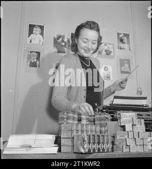 YMCA snapshots from Home- Civilian Photographers at Work, UK, 1944 Betty Brooks, secrétaire du programme « snapshots from Home » du YMCA organise des fournitures de films dans son bureau. Elle est responsable de la « distribution des demandes de clichés des soldats aux snapshots répertoriés dans toute la Grande-Bretagne ». Derrière elle sur le mur sont épinglés plusieurs exemples du travail des photographes amateurs. Banque D'Images