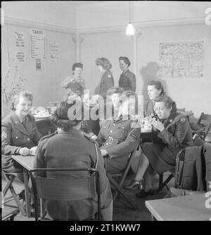 Clubs YWCA- le travail de l'Association chrétienne des jeunes femmes en temps de guerre, Norfolk, Angleterre, Royaume-Uni, 1944 Une scène dans la cantine animée du club YWCA au Close à Norwich. Les militaires britanniques et américains discutent autour d'une tasse de café et d'un en-cas. À gauche, le sergent Terry Phipps du Women's Army corps (WAC), de Buffalo, New York. Le Sgt Phipps a deux enfants adultes : une fille de 18 ans et un fils de 22 ans. Son fils n'est pas assez apte pour se joindre à lui, alors le Sgt Phipps a décidé de servir à sa place. Les avis au-dessus du comptoir comprennent le tarif pour les rafraîchissements (le thé est 1d et le café 2d), un avis Banque D'Images