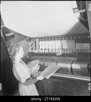 Naissance d'un Bombardier- La production d'aéronefs en Grande-Bretagne, 1942 Une femme travailleuse de guerre bleu recueille des impressions à partir de la machine qui les a publiées, et les ajoute à la pile elle est déjà tenue, à la Handley Page factory à Cricklewood. Banque D'Images