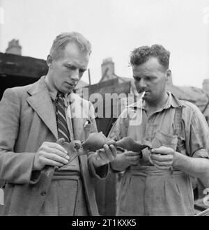 Blitz Repair Squad's Camp Londres- la vie quotidienne avec les équipes de réparation Blitz, Londres, Angleterre, RU, 1944 contremaître général J Wigley (Darlington) et de contremaître H Uttley examiner un morceau de la demeure d'une bombe volante V1. Ils font partie d'une équipe de bâtisseurs qui sont venus à Londres, provenant de diverses régions du pays pour réparer les dégâts causés par ces bombes. Banque D'Images