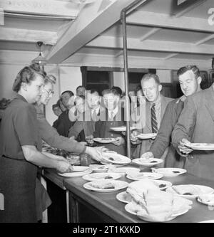 Blitz Repair Squad's Camp Londres- la vie quotidienne avec les équipes de réparation Blitz, Londres, Angleterre, RU, 1944 Les constructeurs de l'équipe de réparation 'Blitz' pour recueillir leur petit déjeuner de femmes du Women's Voluntary Service (WVS) dans le mess hut de leur camp dans le carré d'Onslow. Banque D'Images