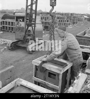 Produits britanniques en gares de triage- anglo-américain la coopération en temps de guerre, la Grande-Bretagne 1943 Brumm, Bob Pfc de 141 South Oak Street, West Point, New York, attache une cuisinière à une grue dans un triage, quelque part en Grande-Bretagne. Ce poêle est l'un d'un lot qui vient d'arriver d'Écosse. Banque D'Images