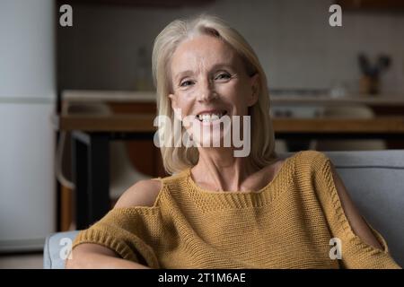 Heureuse blonde senior femme des années 60 souriant à la caméra, regardant, parlant Banque D'Images
