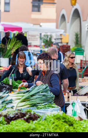 Une femme française locale tient son étal de légumes frais et de produits au marché alimentaire en plein air dans la vieille ville, Annecy, France Banque D'Images