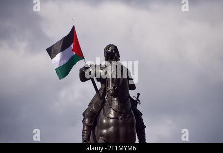 Londres, Royaume-Uni. 14 octobre 2023. Les manifestants placent un drapeau palestinien sur la statue équestre de Charles Ier à Trafalgar Square pendant la manifestation. Des milliers de personnes ont défilé en solidarité avec la Palestine alors que la guerre Israël-Hamas s’intensifie. Crédit : SOPA Images Limited/Alamy Live News Banque D'Images