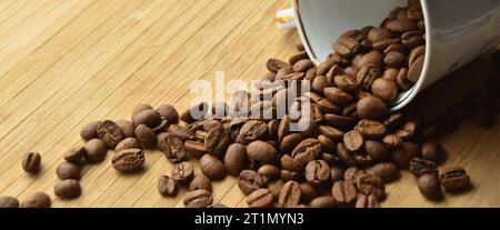 Grains de café frais soigneusement sélectionnés et torréfiés à l'intérieur de la tasse, sur une table en bois Banque D'Images