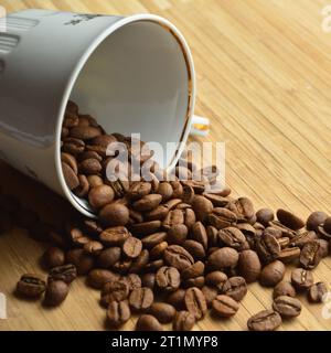 Grains de café frais soigneusement sélectionnés et torréfiés à l'intérieur de la tasse, sur une table en bois Banque D'Images