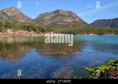 La marée haute sur les eaux de mer propres et claires de la côte rocheuse immaculée du parc national de Freycinet en Tasmanie a les dangers en arrière-plan Banque D'Images