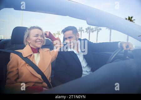 Heureux mature caucasien joyeux copule conduisant un cabrio et souriant heureux dans un roadtrip de vacances Banque D'Images