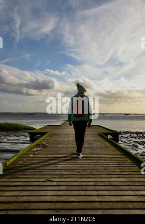 Une dame marchant le long de la vieille jetée en bois Banque D'Images