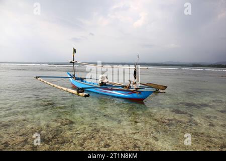 Un petit bateau de pêche indonésien amarré sur un récif corallien à Sumatra Banque D'Images