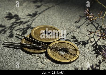 Aiguilles d'acupuncture et pièces de monnaie anciennes sur la surface de la pierre Banque D'Images