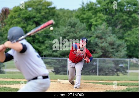 Spring Grove, Illinois, États-Unis. Lanceur livrant un terrain à un batteur en attente pendant un match de baseball amateur masculin dans la banlieue de Chicago. Banque D'Images