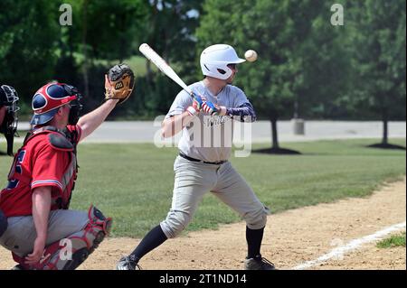 Spring Grove, Illinois, États-Unis. Batteur qui sort un terrain élevé de la zone de frappe pour une balle. Banque D'Images