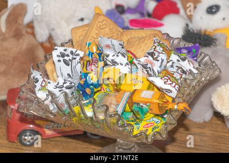 Chisinau, Moldavie - 10 octobre 2021 Un bol en verre rempli de bonbons et d'animaux en peluche. Banque D'Images