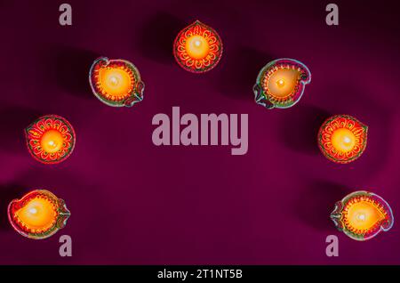 Lampes colorées en argile diya allumées pour célébrer le festival Diwali sur fond violet. Banque D'Images