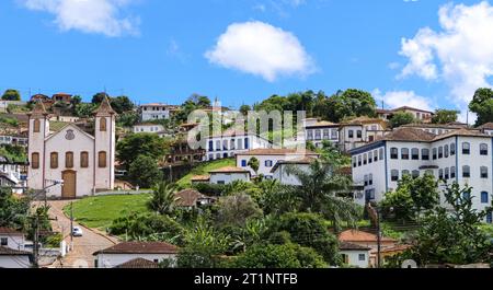 Vue sur la ville minière historique de Serro nichée sur une colline, ciel bleu et nuages blancs, Minas Gerais, Brésil Banque D'Images