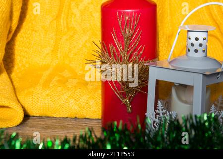 Décorations de Noël et décorations avec un pull jaune et une bougie rouge sur une surface en bois. Banque D'Images