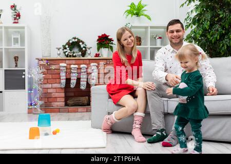 Maman, papa et enfant passent Noël ensemble dans une maison pleine de décorations de Noël Banque D'Images