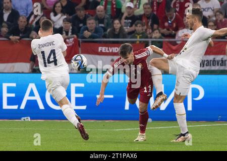 Budapest. 14 octobre 2023. Andrija Zivkovic (à gauche) et Strahinja Erakovic (à droite), de Serbie, affrontent Milos Kerkez, de Hongrie, lors du match de qualification du Groupe G de l’UEFA Euro 2024 entre la Hongrie et la Serbie à Budapest, en Hongrie, le 14 octobre 2023. Crédit : Attila Volgyi/Xinhua/Alamy Live News Banque D'Images