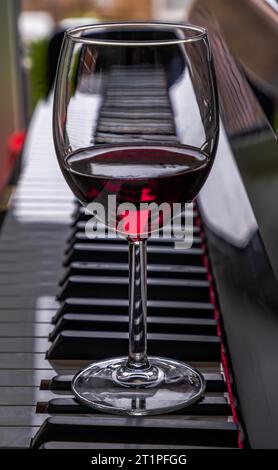 Verre de vin rouge sur clavier de piano. Concept de musique et de vin, espace pour le texte, mise au point sélective. Banque D'Images