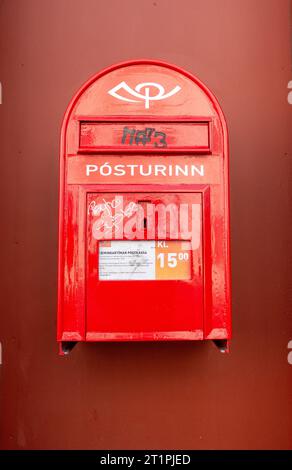 Íslandspóstur ou Pósturinn boîte postale rouge Islande fixée au mur avec un peu d'étiquetage Graffiti sur la boîte postale Reykjavik Service de lettres postales islandaises Banque D'Images