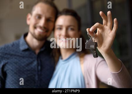 Sourire heureux jeune couple marié tenant les clés de la nouvelle maison Banque D'Images