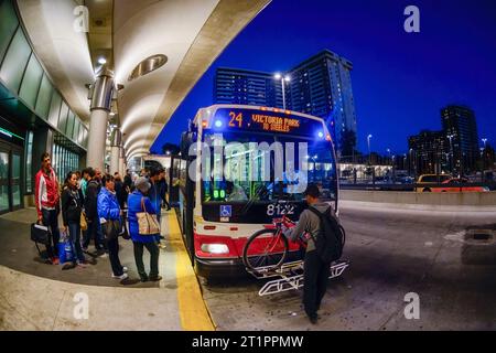 Les personnes embarquant dans un autobus public de la Toronto Transit Commission à la gare Victoria Park. Un homme pose une bicyclette dans le porte-bagages avant du véhicule à moteur Banque D'Images