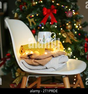 Pulls pliés sur une chaise sur le fond d'un arbre de Noël Banque D'Images