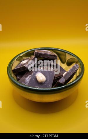 Vue de dessus d'un bol de barres de chocolat cassées sur un fond jaune Banque D'Images