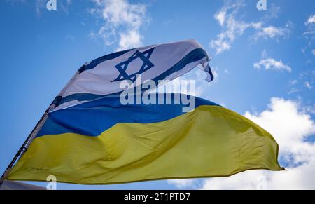 14 octobre 2023, Hesse, Francfort-sur-le-main : un drapeau israélien et un drapeau ukrainien flottent sur un poteau lors d'un rassemblement pro-israélien devant l'église Paulskirche à Francfort-sur-le-main, en Allemagne, auquel ont participé environ 1 000 personnes. Photo : Frank Rumpenhorst/dpa Banque D'Images